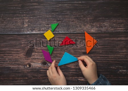children's hands and wooden puzzle game on a wooden background. Top view The concept of independent children's educational toys in school. thinking