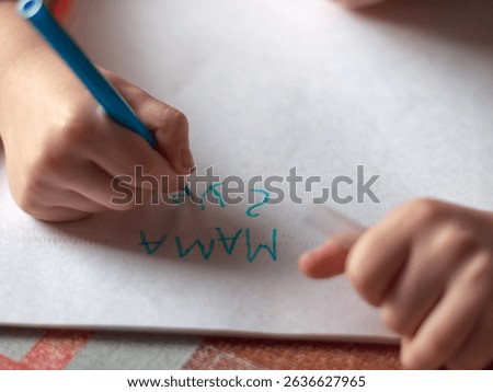 Children's hands write the first word MOM, learn to write.