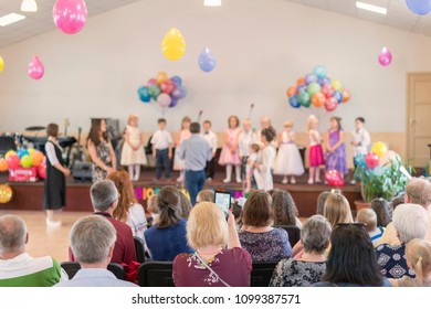 Children's Holiday In Kindergarten. Children On Stage Perform In Front Of Parents. Image Of Blur Kid 's Show On Stage At School , For Background Usage. Blurry