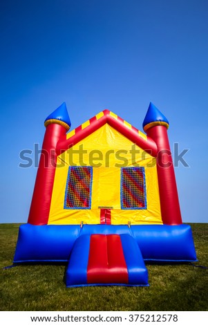 Children's inflatable bouncy castle house in a yard.