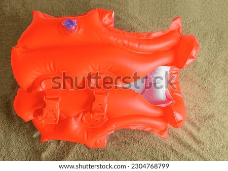 Children's inflatable life jacket lies on the sand.