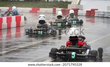 Children's karting competitions. A group of children rushes through the cartodrome in the rain. Selective focus.                               