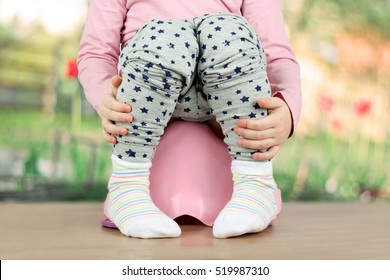 Children's legs hanging down from a chamber-pot on a green background