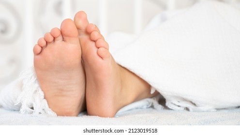 Children's legs stick out from under the blanket. Close up of a children's feet, copy space. High quality photo - Shutterstock ID 2123019518