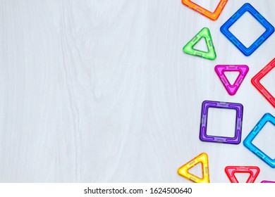 Children's magnetic designer or constructor. Datails, geometric shapes on white wooden background. Flat lay, copy space.