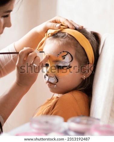 childrens makeup face paint drawings Girls face painting. Little girl having face painted on birthday party. closed eyes. kids birthday party. High quality photo