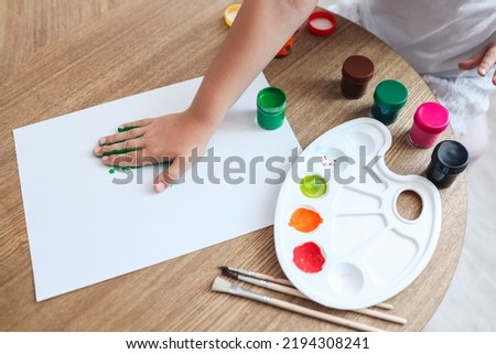 Children's master class in drawing, the child makes a handprint with paint.