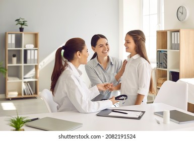 Children's medical care. Happy mother and daughter at medical examination at friendly female pediatrician. Smiling doctor and mother encourage teenage girl during medical consultation at hospital. - Powered by Shutterstock
