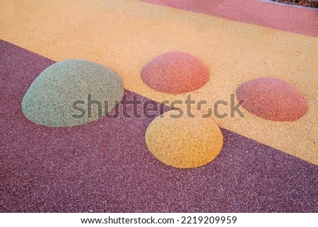 Children's mounds covered with a rubberized coating of lilac pink yellow brown color on the playground on a clear sunny day. Sports Recreation Entertainment.