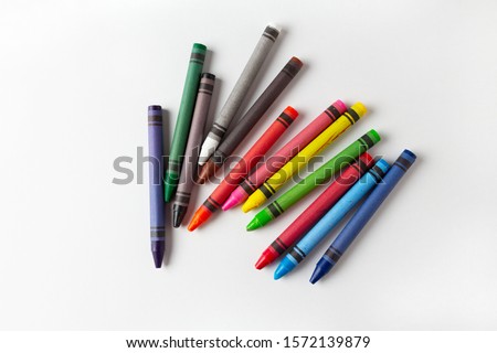 children's multi-colored wax crayons for drawing on a white landscape sheet