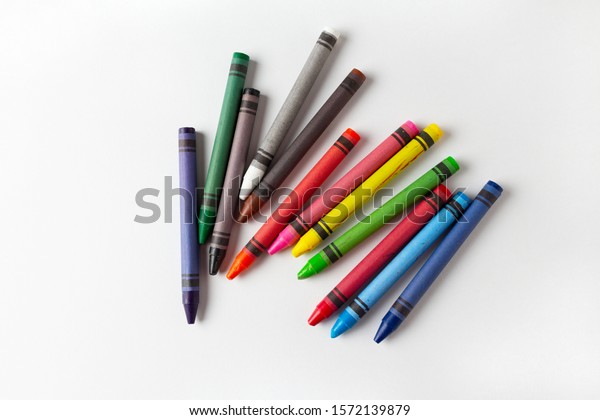 children's multi-colored wax crayons for drawing on a white landscape sheet