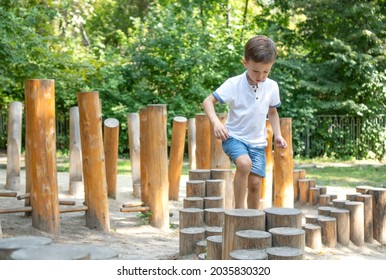 Children's Obstacle Course On A Modern Playground. Kid Crossing A Wooden Bridge. Development Of The Child's Agility And Courage.