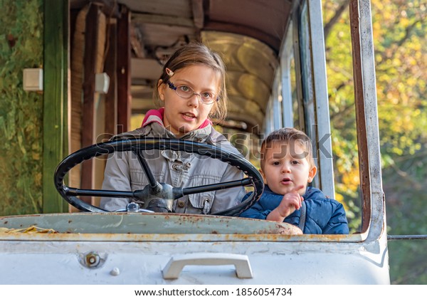 Childrens play in\
an abandoned bus. A girl drive a bus. The girl turns the steering\
wheel in the abandoned bus.\

