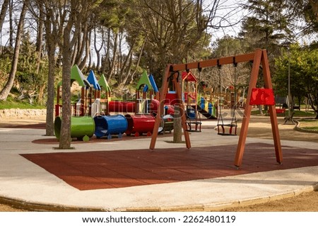 Children's play area with swing, slide, climbing ladder, sandbox, bicycle and toys.