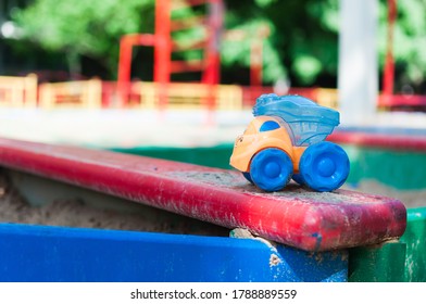 Children's Playground With Empty Sandbox And Abandoned Colorful Toy Car.