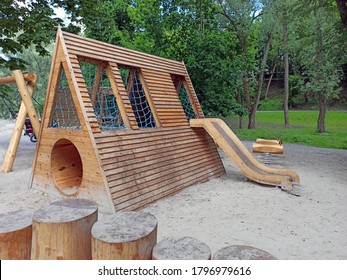 Children's playground equipped with wooden swings and slides. A modern children's slide made of wood and natural materials. - Powered by Shutterstock