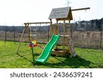 A childrens playground in the garden is made of unpainted wood.