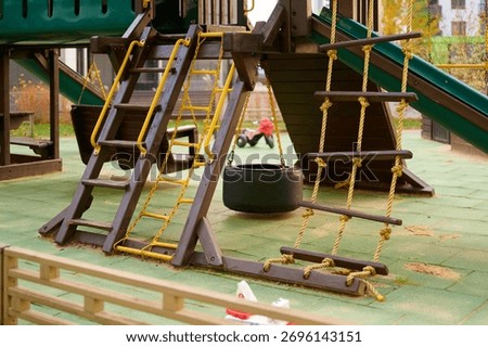 children's playground with slide, climbing structures, and tire swing in park setting. vibrant play area encourages outdoor activity and adventure for kids. safe, fun recreational spot.