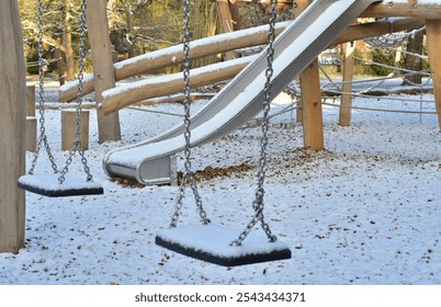 children's playground with a slide and swings under the snow - Powered by Shutterstock