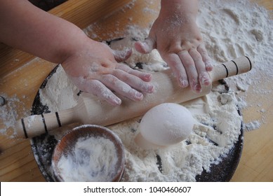 Children's rolling pin for dough. The child kneads the dough with his hands. The baby's hand sifts the flour. - Powered by Shutterstock