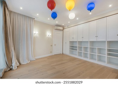 Children's room with built-in white wardrobe. Original ceiling lights in the form of multicolored balls. Unfurnished. - Powered by Shutterstock