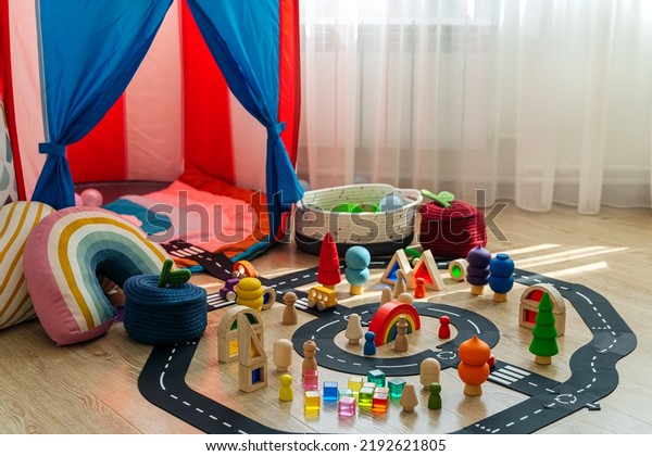 Children\'s room with a play tent and toys. A toy\
town built in a children\'s room. Car track, toy cars, trees and\
wooden blocks for games in playroom. Educational game for toddler\
in modern nursery.