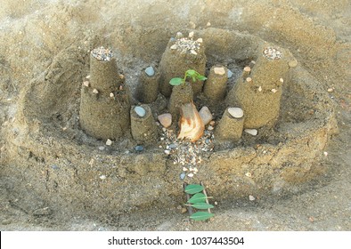 Children's Sand Castle With Pebbles, Shells And Leaves For A Bridge Over The Moat