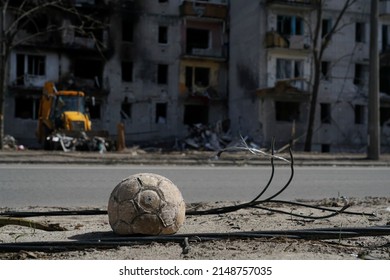 A children's soccer ball lies near the road against a building destroyed by an explosion in the war in Ukraine. Nearby are the wires of a broken power line.