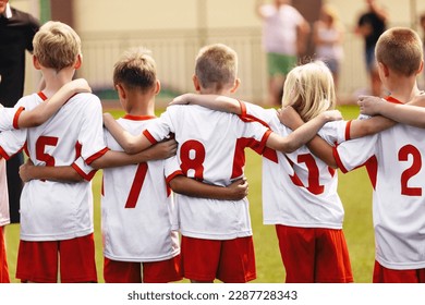 Children's soccer football team. Athletic boys teammates in junior soccer team united in team standing together at grass sport field. Kids in white soccer jersey shirts - Powered by Shutterstock