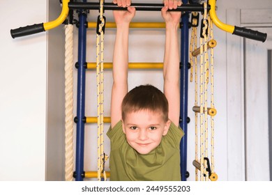 Children's sports. Small active boy hangs on horizontal bar, plays sports at home. Happy childhood. Child is doing pull-ups on horizontal bar. Child development concept. - Powered by Shutterstock