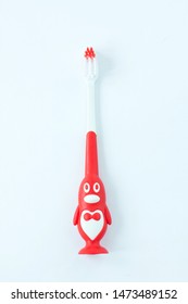 Children's Toothbrush In A Form Of Red Penguin On A White Background Isolated. Kids Oral Care, First Deciduous Teeth Hygiene, Bathroom Supplies, Dentistry.