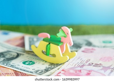 A Children's Toy Swing Is On Paper Money. Conceptual Photo, Cost Of Maintaining A Child, Expenses For Raising Food, Clothing And Education.