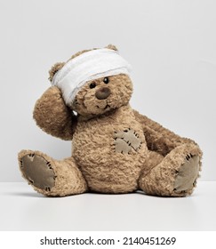 Children's Toy Teddy Bear Sits With A Bandaged Head. Childhood Trauma Concept