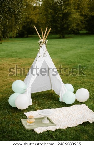 Children's wigwam party, outdoor photo zone decor. A white wigwam with balls stands in the park. Birthday picnic.