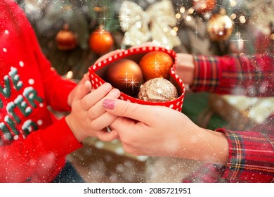 Childrens And Womens Hands Are Holding A Box With Christmas Toys. New Year Concept