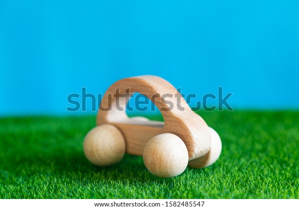 Children\'s wooden toy car on the grass Wooden\
car on the green grass blue\
background