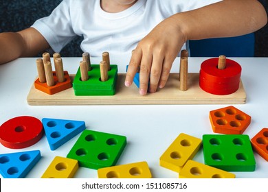 
Children's wooden toy. The child collects a sorter. Educational logic toys for kid's. Children's hands close-up. 
Montessori Games for Child Development