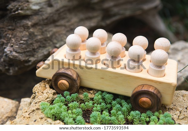 Children\'s\
wooden toys. Children wooden car with passengers outdoors. Natural\
wood construction set. Educational equipment.\

