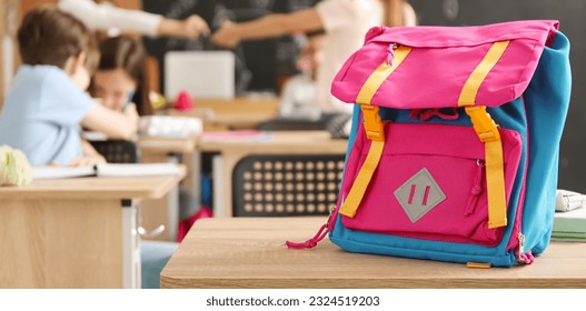 Child's backpack on desk in classroom - Powered by Shutterstock