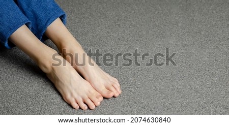 Child's bare feet. Girl's legs in jeans. Sitting on the floor.