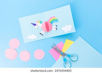 Child's craft project with scissors on paper, showcasing a unicorn-themed card template in blue colors. Perfect for DIY activities and artistic learning. - Powered by Shutterstock