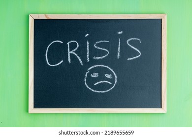 Child's Drawing Of A Crisis With A Very Sad Face. Drawing On Black Board With Chalk