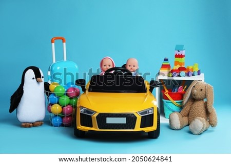 Child's electric car with other toys on light blue background