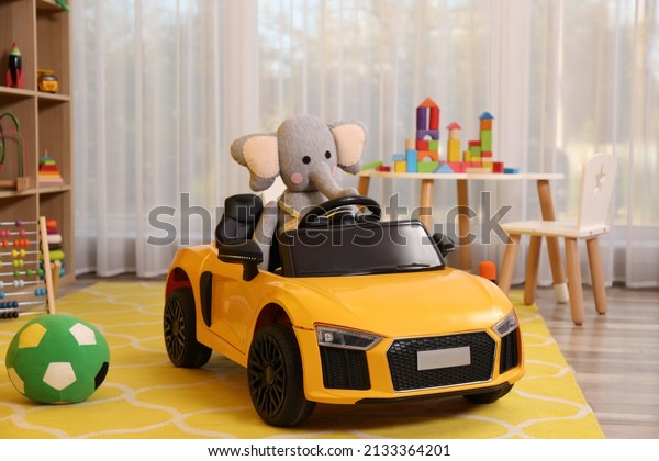 Child\'s\
electric car with toy elephant in\
playroom