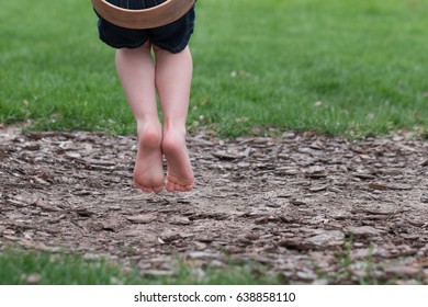 Child's feet on playground swing alone from behind
