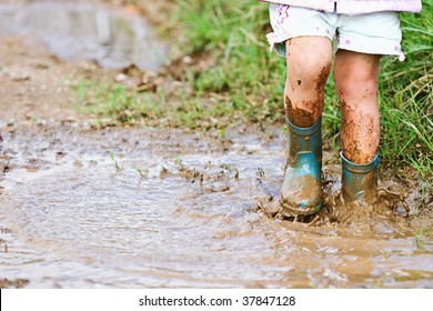 Child's Feet Stomping In A Mud Puddle.