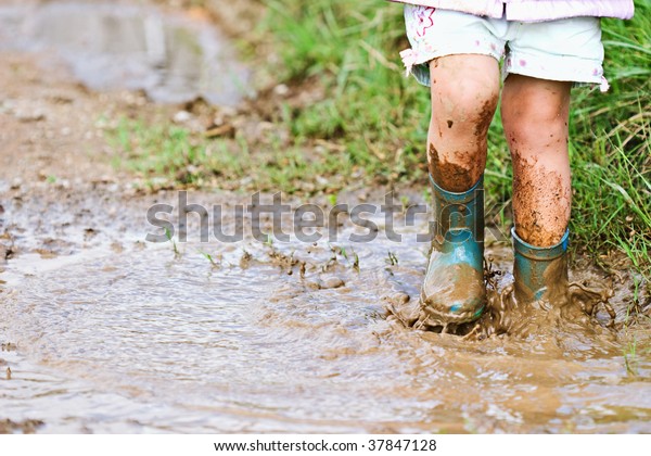 泥だらけの水たまりの中で子どもの足が踏み鳴らす の写真素材 今すぐ編集