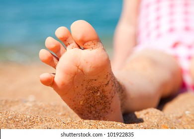 child's foot is close to the sandy beach of the seaside resort - Powered by Shutterstock