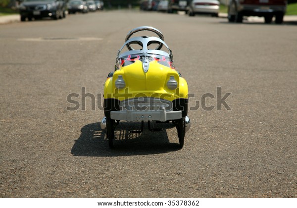 childs generic pedal\
car on a city street