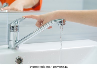 The child's hand closes the water from the mixer by pressing the finger on the handle